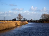 Dutch canal bordered by reed with white windmill in background  Dutch canal bordered by reed with white windmill in background : architecture, blue sky, building, canal, cloud, clouded sky, clouds, countryside, destinations, dutch culture, europe, european, historic, history, Holland, Kinderdijk, monument, Netherlands, non-urban scene, reed, rural, rural landcape, rural scene, South Holland, the past, travel, water, water management, windmill