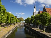 Canal in historic Dutch  town Sloten, Friesland  Canal in historic Dutch  town Sloten, Friesland : sleat, sloten, friesland, de friese meren, Europe, european, fryslan, Holland, Netherlands, blue, canal, coud, espalier, frisian, green, historic, history, in a row, many, road, row, sky, street, the way to go, town, tree, trees, urban landscape, urban scene, water, white clouds, church, tower, bridge, step gable