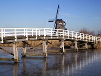 NL, Zuid-Holland, Molenwaard, Kinderdijk 3, Saxifraga-Roel Meijer  Wooden bridge in Unesco World Heritage Site Kinderdijk, South Holland, Netherlands : icy, winter, wintertime, blue sky, reed, unesco world heritage site, Kinderdijk, South Holland, Holland, Netherlands, windmill, wooden, bridge, historic, building, monument, travel destinations. canal, ice